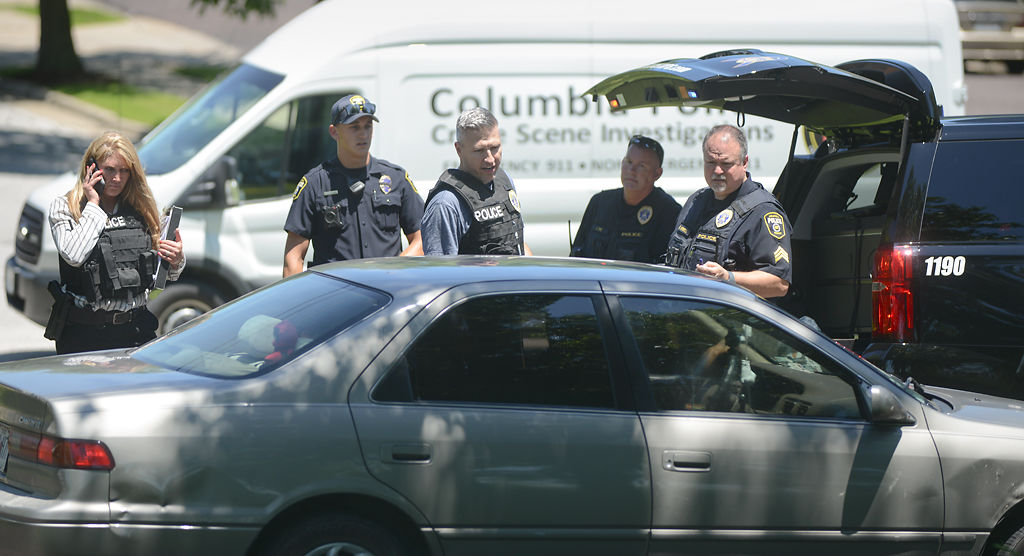 Officers talk to a resident near a shooting
